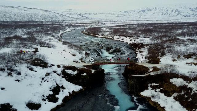 4K. Aerial view over Bruarfoss waterfall. Flowing of turquoise water and surrounded by fresh snow of winter. famous destination in South Iceland