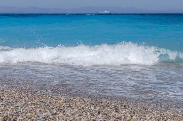 Sand pebble beach with bubbles  summer close up of small wave