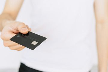 A young man holds a bank card in his hand. Іsolated white background