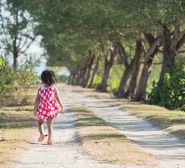 kid walking alone between trees