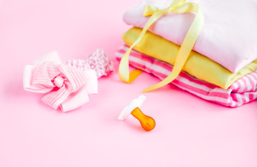 newborn stuff, clothes and pacifier for baby girl on pink background