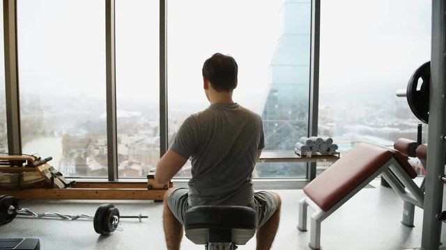 Regular young fitness man making stretching exercises before gym workout