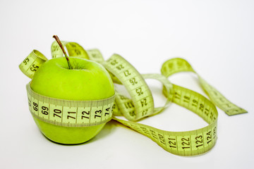 diet, healthy eating, food and weigh loss concept. Measuring tape wrapped around green apple on...
