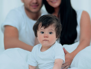 Happy couple and son sitting in bed