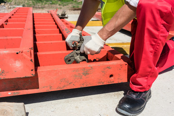 Low-angle view of a serious blue-collar worker installing metallic framing while working at the foundation of a building under construction