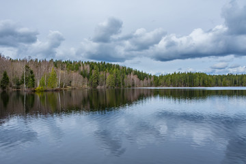 Lake reflection of the lakeshore forest and cloudy sky. Taken along the Bergslagsleden hiking trail, in nature reserve Ånnaboda in central Sweden.
