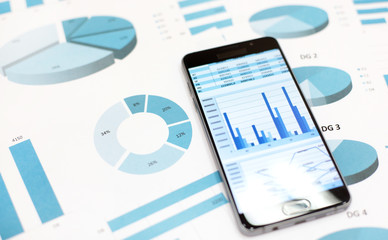 Business charts and graphs on paper and in smartphone