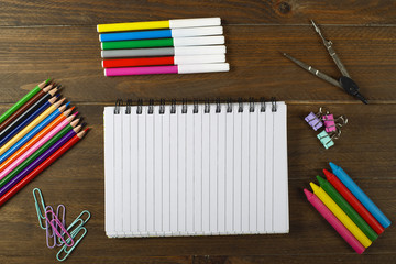 Obraz premium Colored pencils, compass, stationery and notebook on wooden table. Back to school concept.