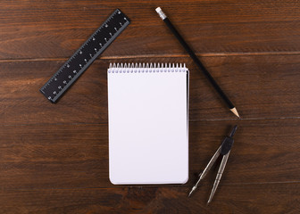 Notebook empty together pencil, compass and ruler on wooden table. Stationery. Concept of Back to shool.