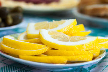 Yellow lemon slice standing on a white plat on table