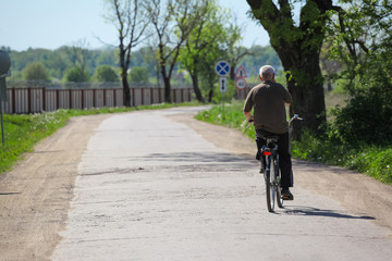 Fototapeta premium a man is riding a bicycle on a country road