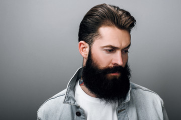 Close up of handsome hipster fashionable young Caucasian male with thick beard wearing trendy denim...