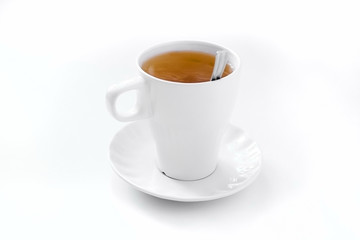 a full cup of brewed black tea with a saucer and a spoon on a white table