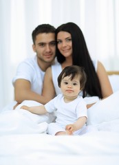 Fototapeta premium Portrait of a joyful family sitting on the bed at home