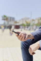 man using a smartphone next to the beach