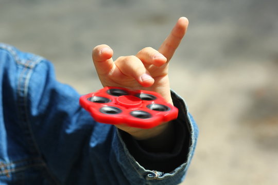 Close up of boy's hand playing with red toy fidget spinner
