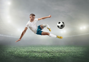 Soccer player on a football field in dynamic action at summer day - obrazy, fototapety, plakaty
