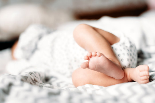 Newborn baby feet close up, unrecognizable baby lying on bed. Soft focus. Newborn background concept