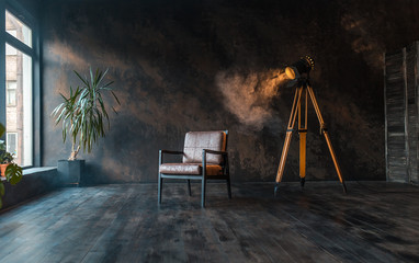 retro spotlight on tripod in grunge wall background with retro brown armchair