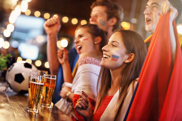 Obraz na płótnie Canvas Group of friends watching soccer in pub