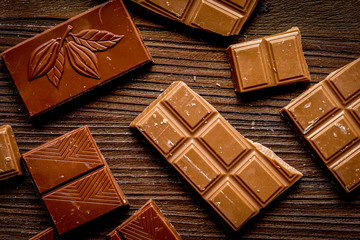 black and milk chocolate pieces wooden table background top view