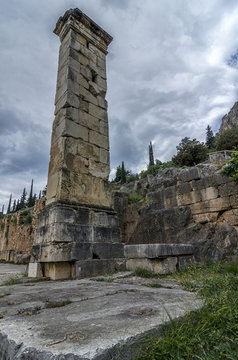 Delphi Town, Phocis - Greece. The Pillar of Prusias II. View at the archaeological site of Delphi. It was constructed in honour of king Prusias II of Bithynia. Dramatic cloudy sky