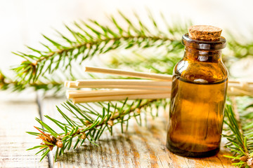 fir branches and spruce aroma oil on wooden table background