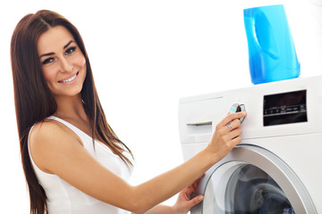 Portrait of young housewife with laundry next to washing machine