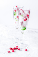 ice cubes with red berries and mint in glasses on white backgrou