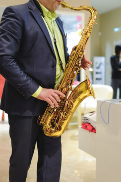 musician plays the saxophone performance at a concert in shopping center of women's clothing store on holiday