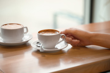 Woman with cup of aromatic coffee at wooden table