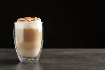 Glass with delicious caramel frappe on table