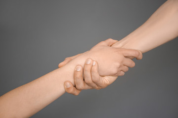 Man and woman holding hands together on grey background. Unity concept