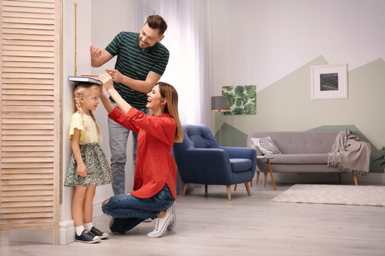 Parents Measuring Their Daughter's Height At Home