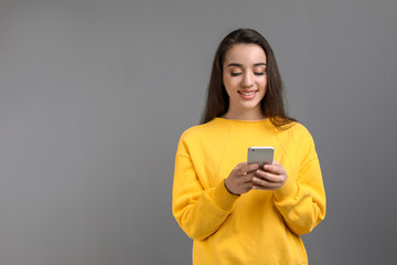 Young woman using phone against color background