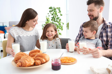Obraz na płótnie Canvas Happy family having breakfast with milk at table
