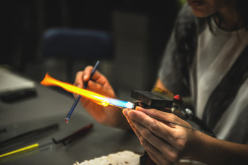 The process of blowing glass products. The manufacture of beads. Hands in the frame. Selective soft focus.