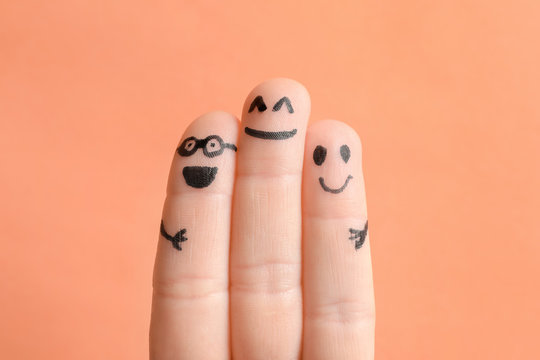 Fingers with drawings of happy faces against color background. Unity concept