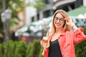 Young woman with mason jar of tasty lemonade outdoors