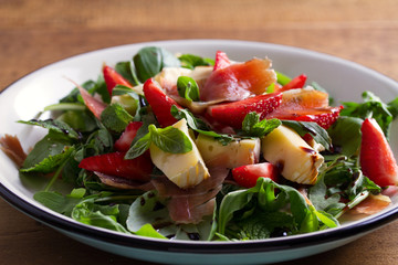 Strawberry, avocado, basil, mint, arugula salad with brie cheese and jamon or prosciutto. Healthy salad bowl