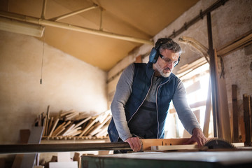 Fototapeta na wymiar A man worker in the carpentry workshop, working with wood.