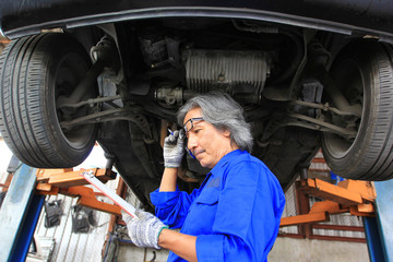 Car mechanic looking at clipboard with inspecting damage in auto repair service.