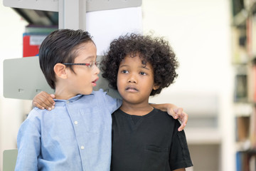 An African American boy stands playing with his friend.Happy kids lifestlye in the Library. Young people explore lifestlye in the Library. Development of Human Resources in Education Concept.
