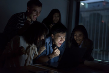 Fototapeta premium Happy businesspeople are working with laptop overtime late at nitgh. They are using laptop to search data. Setup studio shooting.