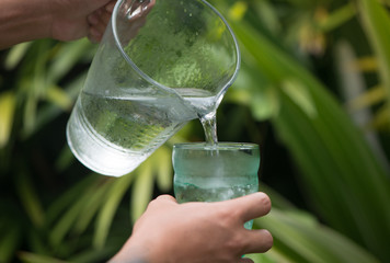 Pouring drinking water in the green glass. 
