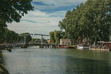 Obraz premium Vecht River with bridge, boats on the banks and brick houses on a sunny day in Weesp. Quiet and pleasant village full of canals and green near Amsterdam. Northern Netherlands.
