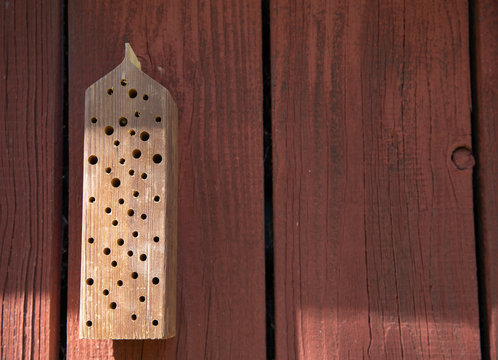 Bee house on red wooden background