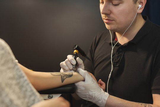 Tattoo artist working with needle on clients arm