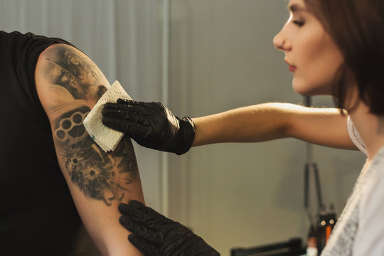 Woman tattoist wiping finished tattoo with napkin