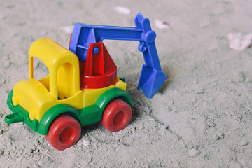 Conceptual photo picture of plastic car in desert. Children's toy. Children play in the sand. The concept of a happy childhood. Kids toys excavator
